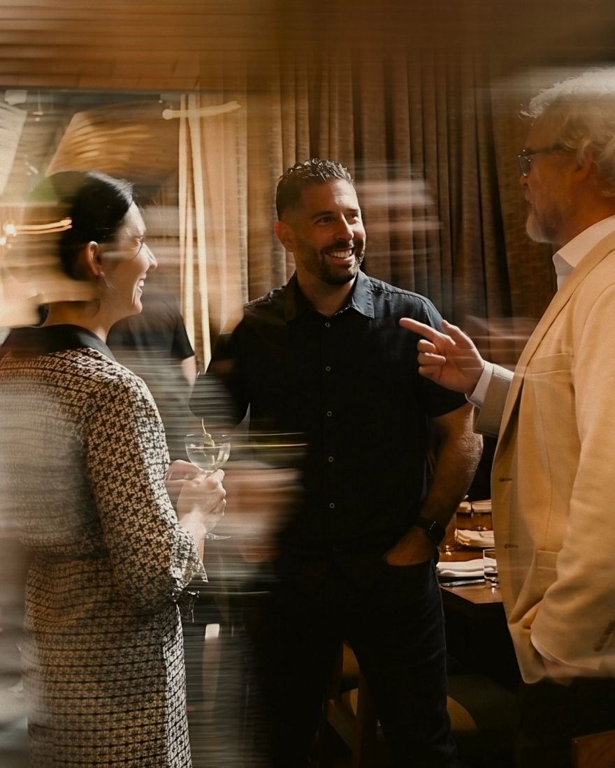 Three attendees talking at an evening reception