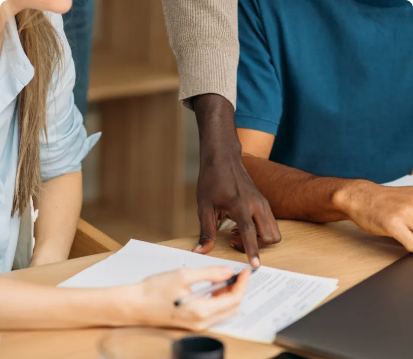 A man and woman collaborate on paperwork at a desk.