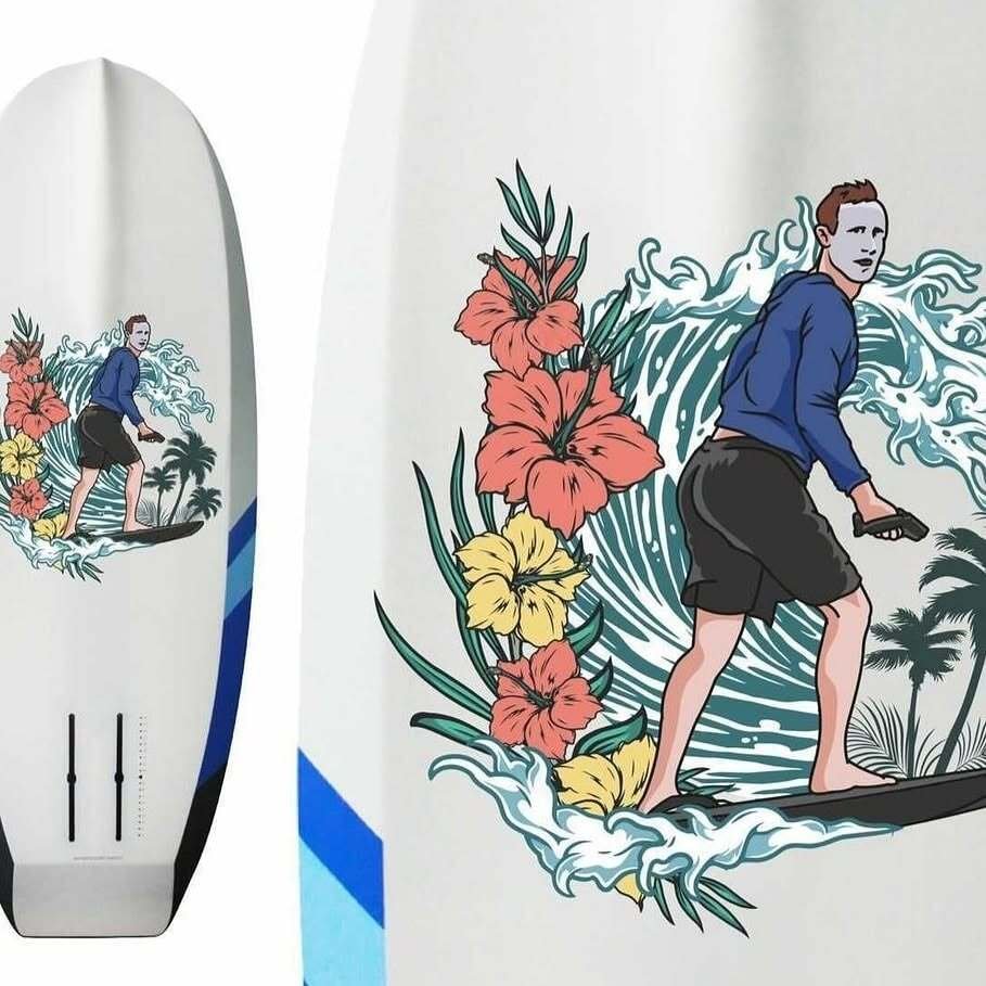 A white surfboard printed with a cartoon of a man in a hoodie surfing a wave beside tropical flowers.