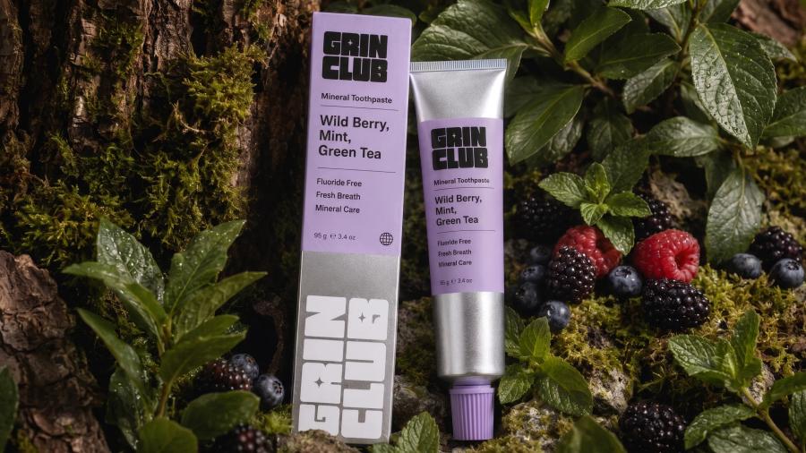 A Grin Club wild berry tube laid on moss with fresh berries around it.