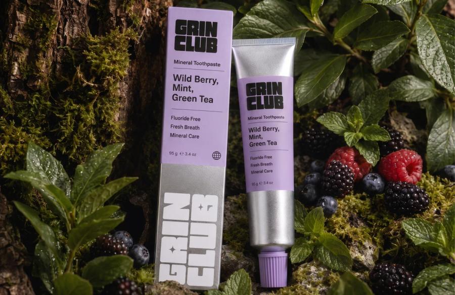 Two Grin Club tubes laid in moss with berries and mint.