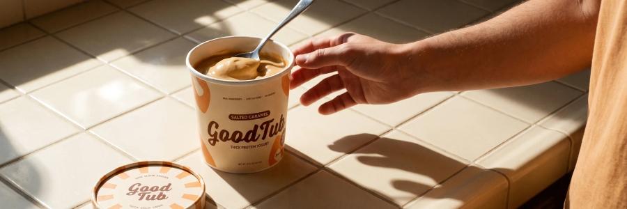 A hand reaching for a GoodTub pot on a sunlit tiled counter.