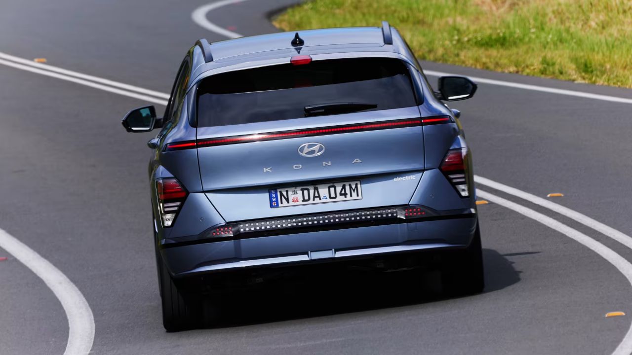 Hyundai Kona in denim blue rear driving on asphalt road