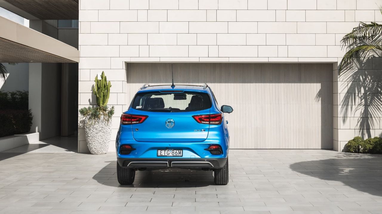 Blue MG ZS EV rear view in front of modern home