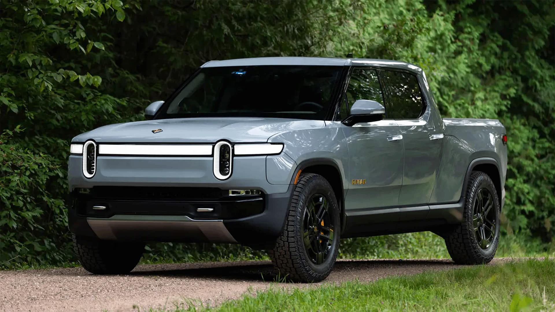 Gret Rivian R1T in off-road inside a forest background