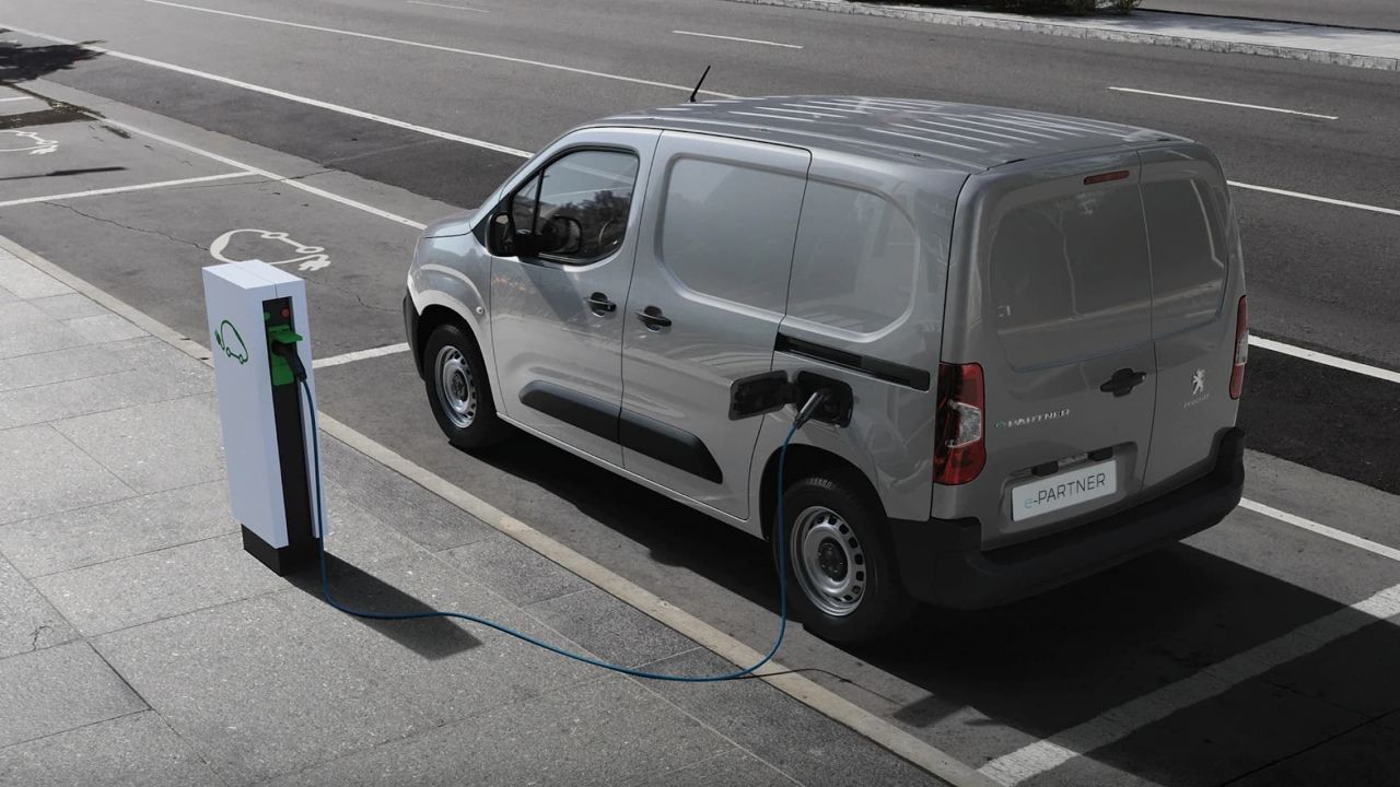 Silver Peugeot e-Partner van rear view charging from streetside AC charger