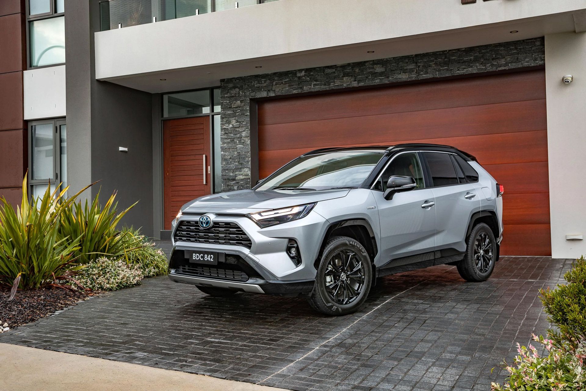 Silver Toyota RAV4 Hybrid parked in front of house driveway