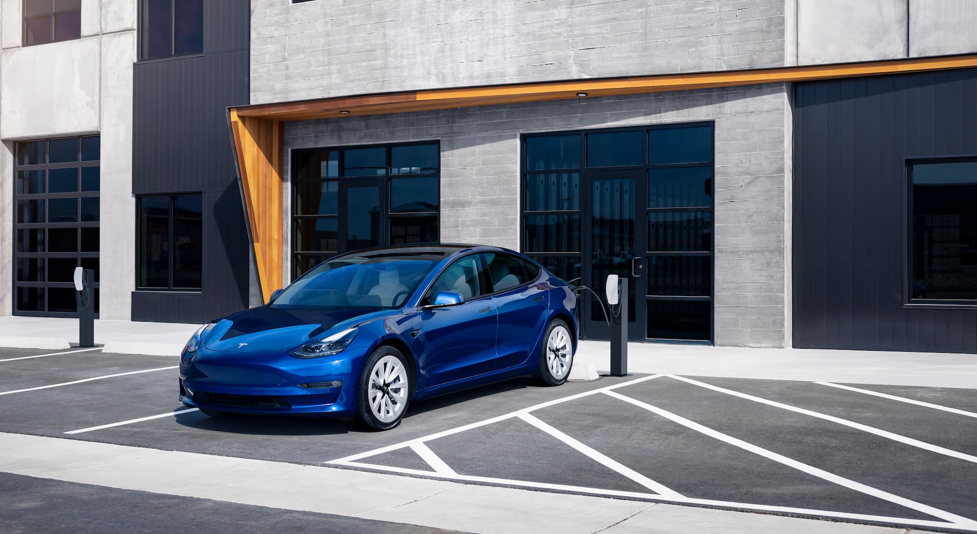 Blue Tesla Model 3 AC charging in front of office