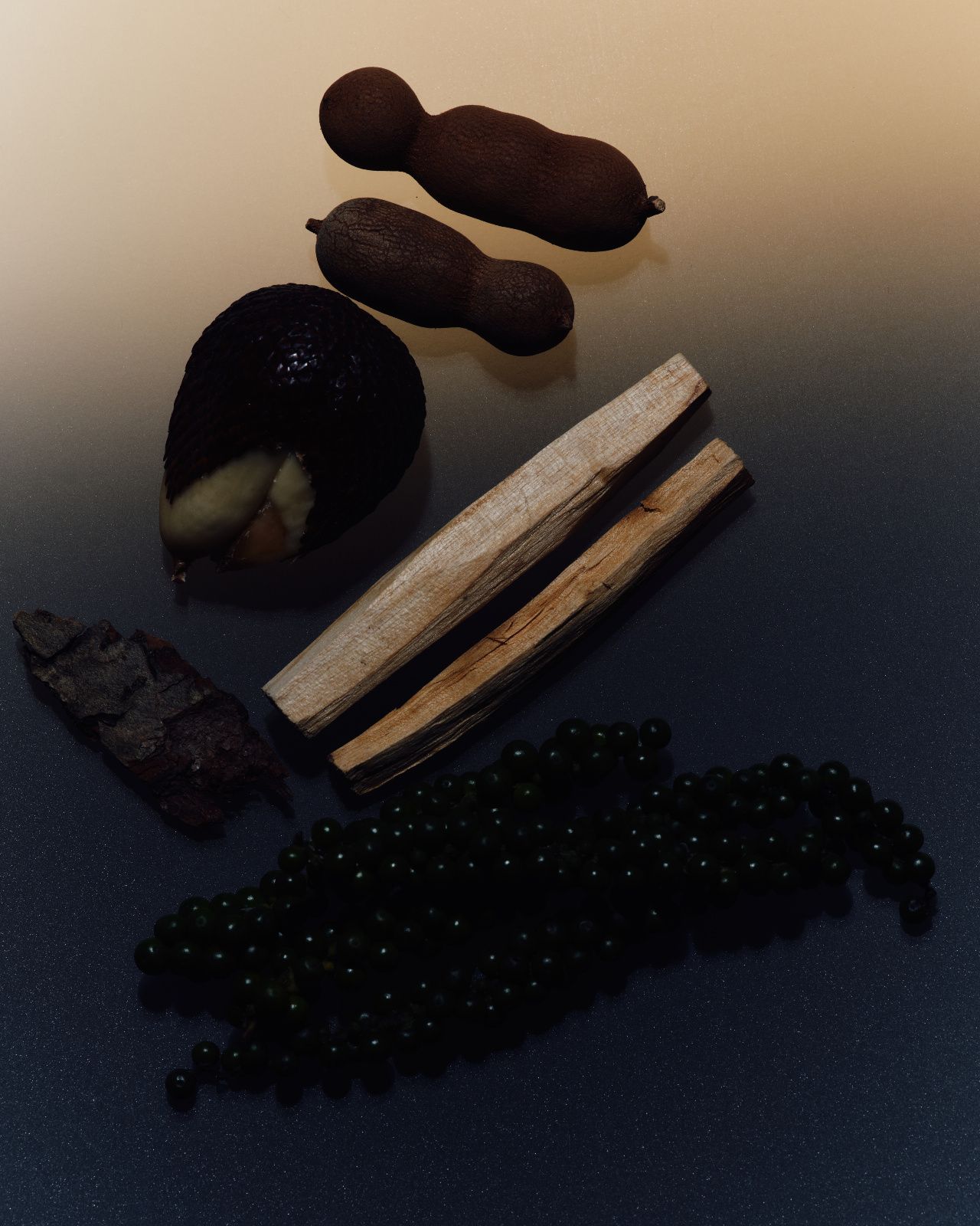 A flat lay of natural tamarind pods, palo santo sticks, dried bark, and dark wood beads on a warm-toned surface.