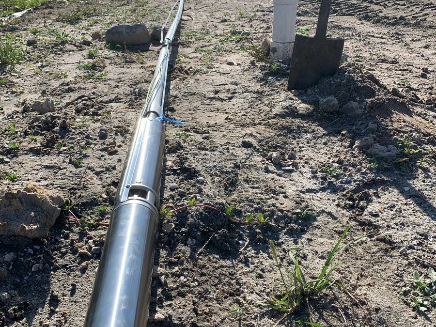 A submersible pump and its pipe laid out across a yard