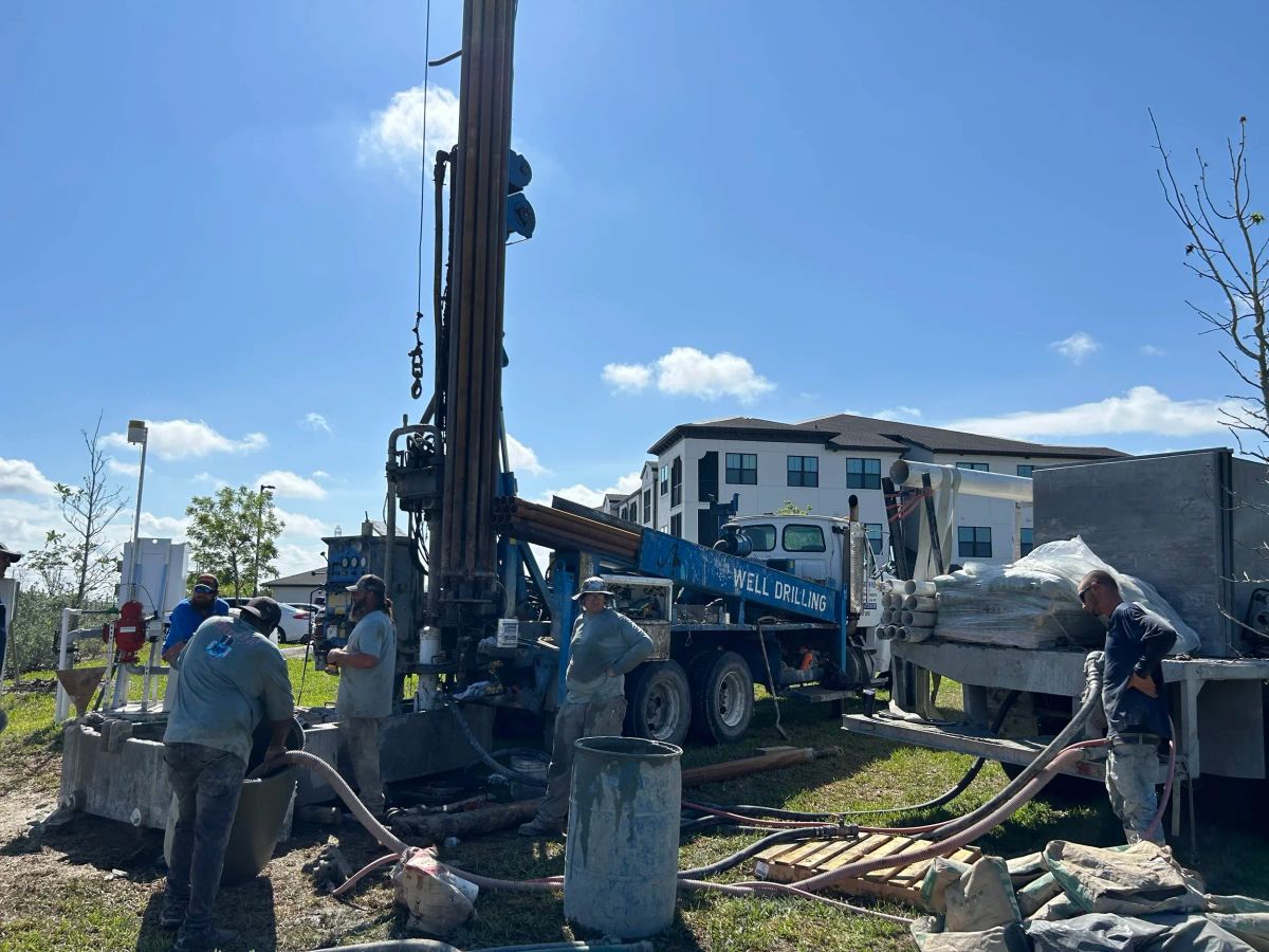 Drill rig and crew working on a lot beside an apartment building