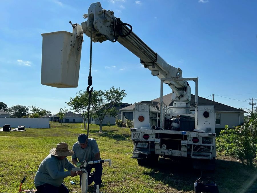 Two crew members at a wellhead while a boom truck lifts the pump line