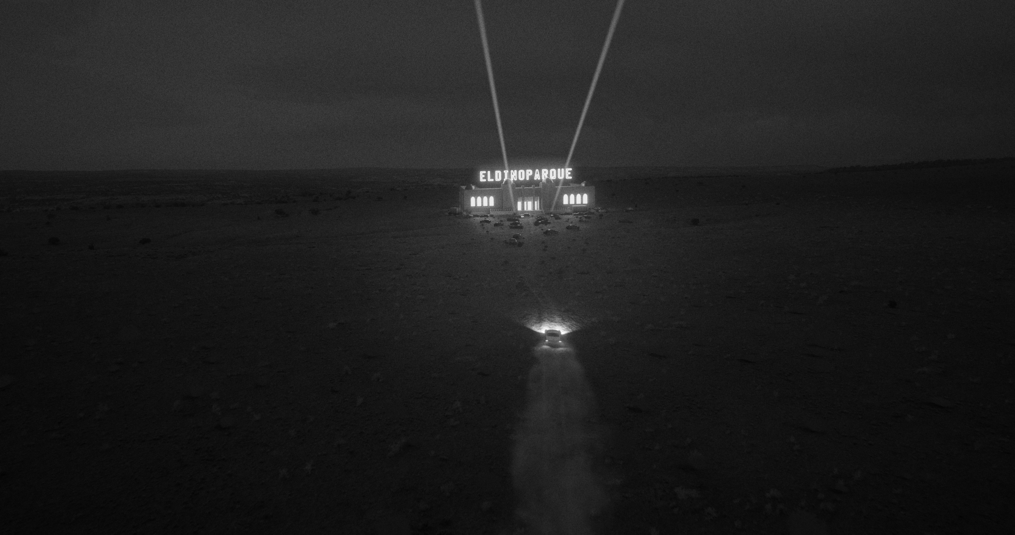 A car driving up to a nightclub in the middle of the desert