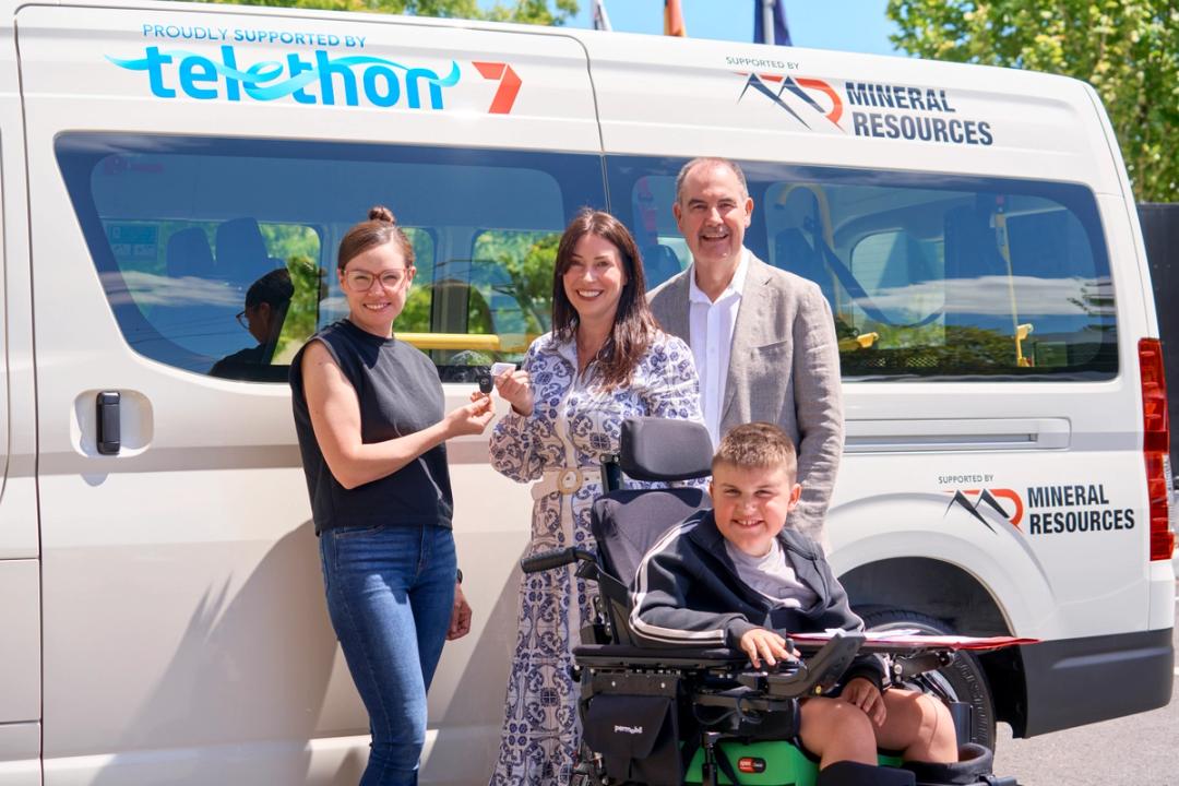 Three adults and a child in front of a van