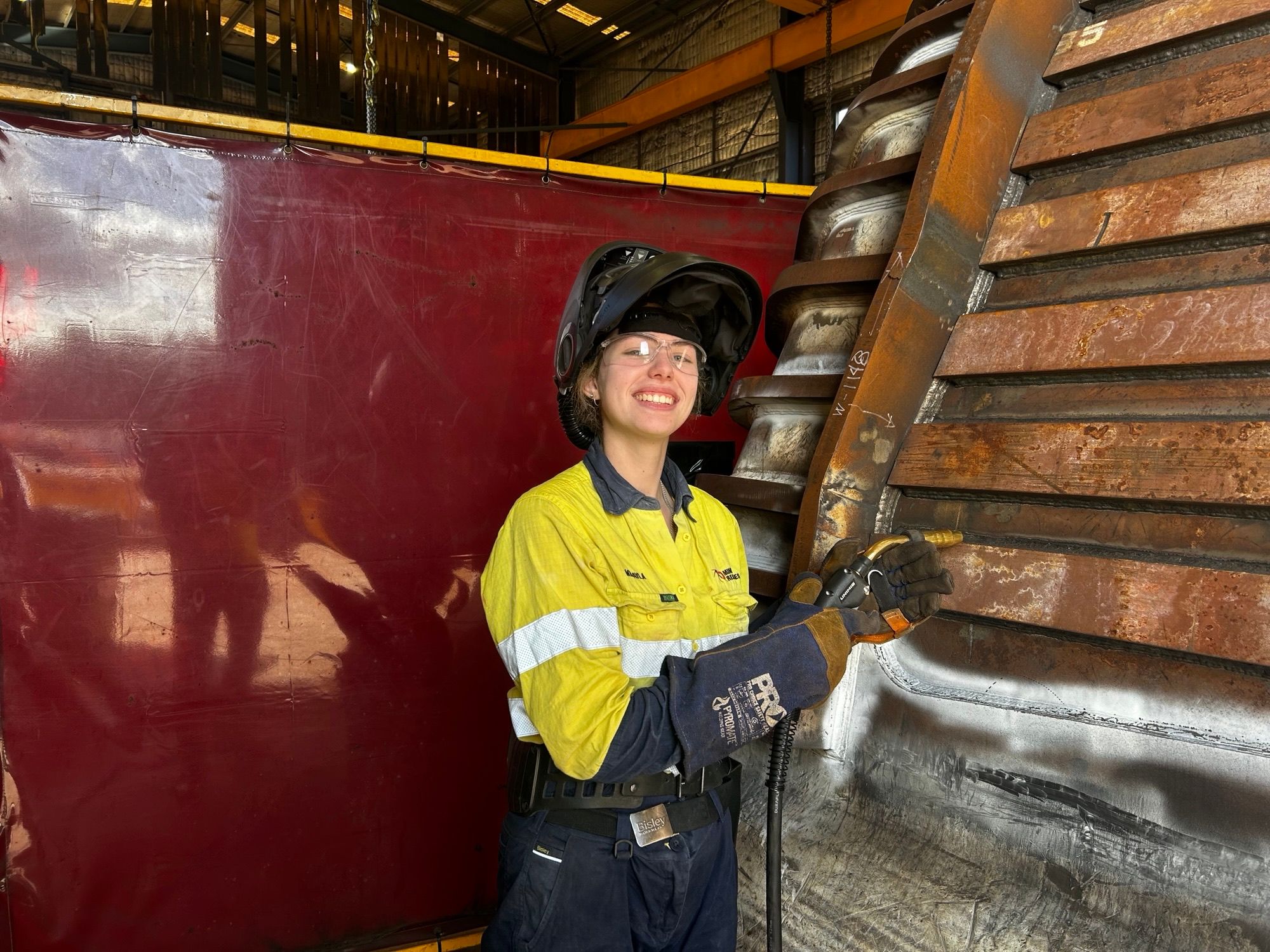 Woman (Mikayla) standing in front of a piece of machinery