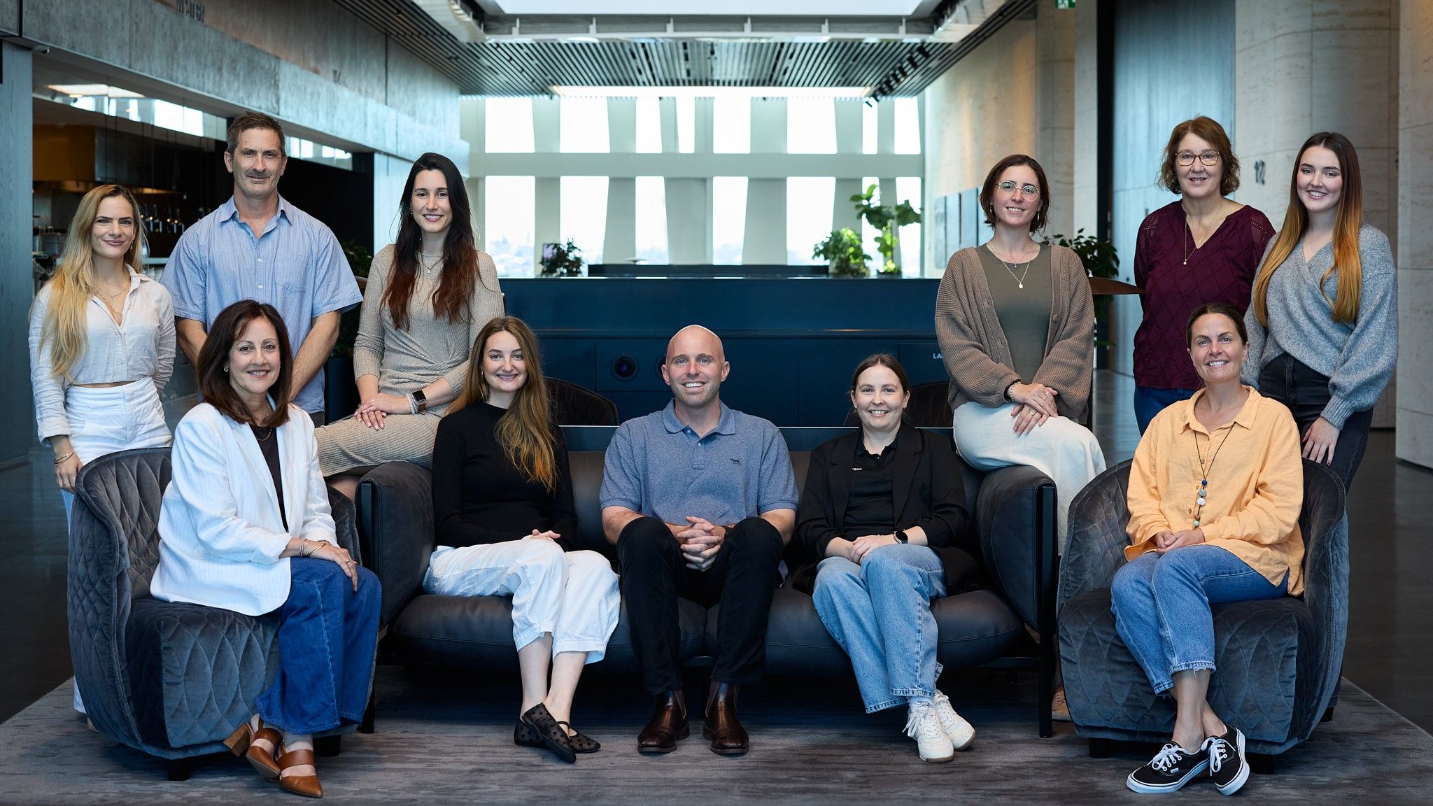 A group of people sitting and standing together smiling