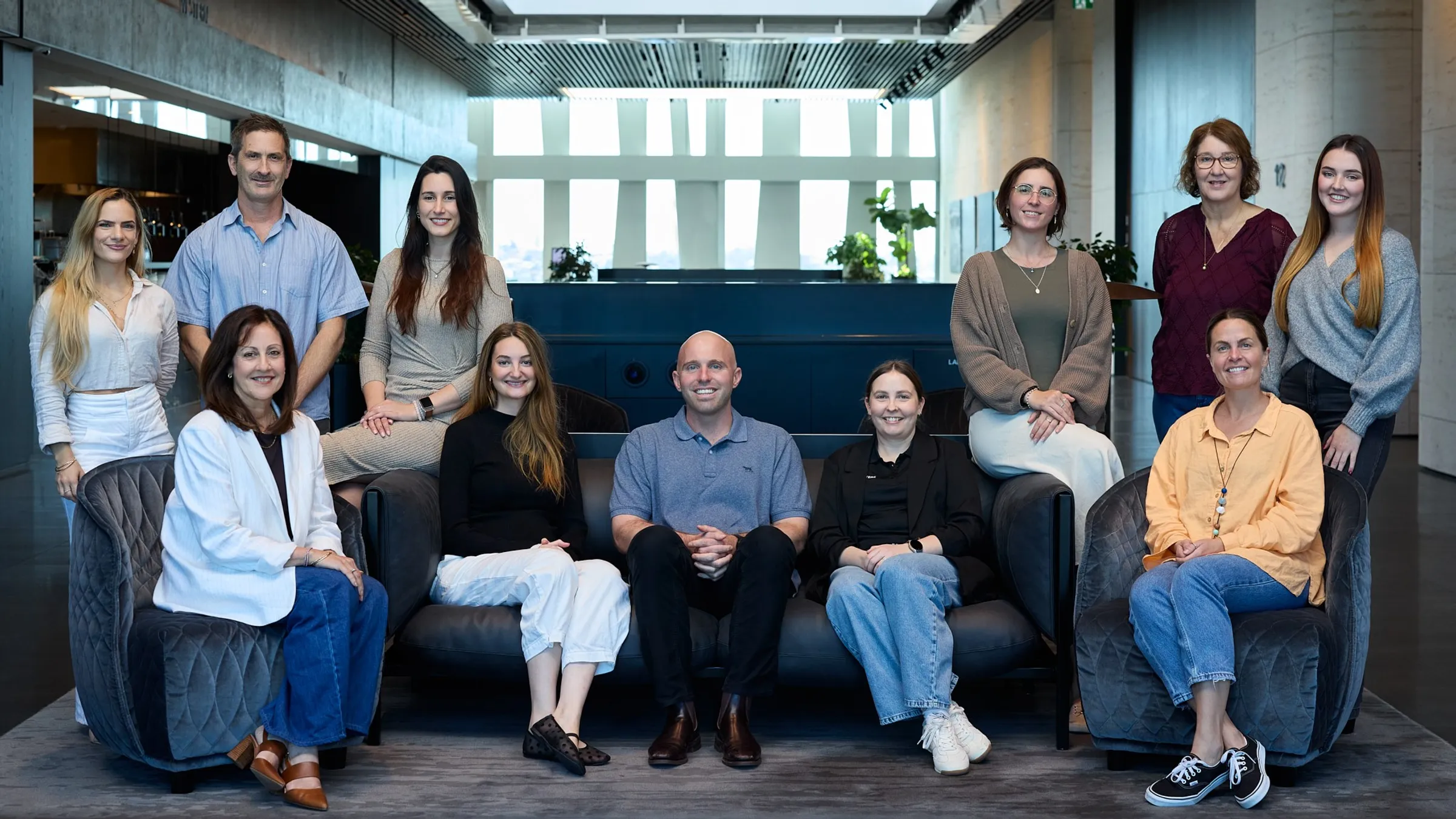 A group of people sitting and standing together smiling