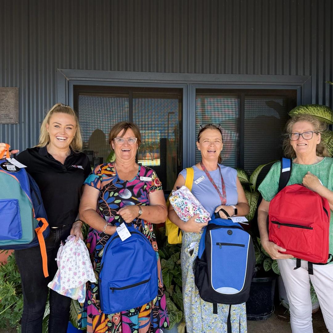 Four women standing with backpacks for kids