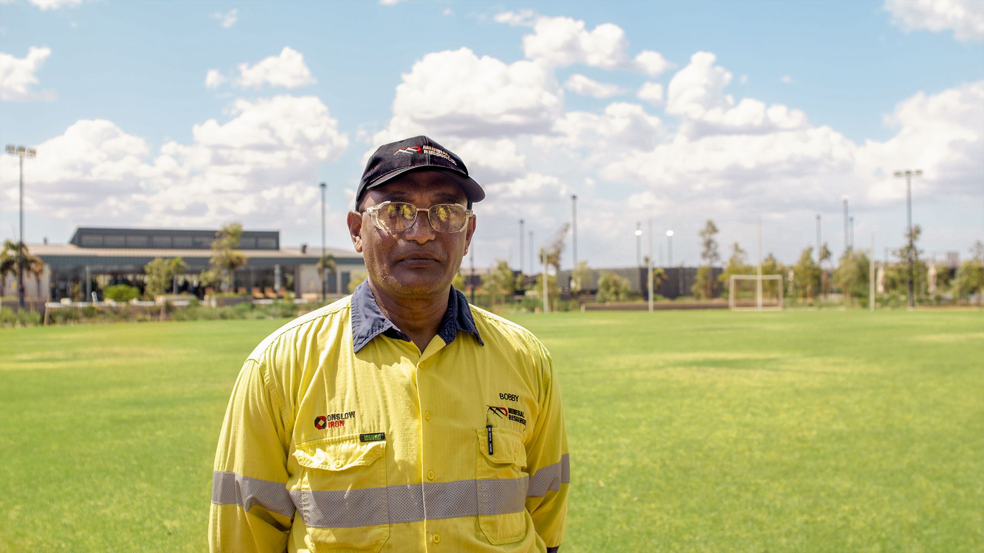 Man in sunglasses and high vis standing on an oval