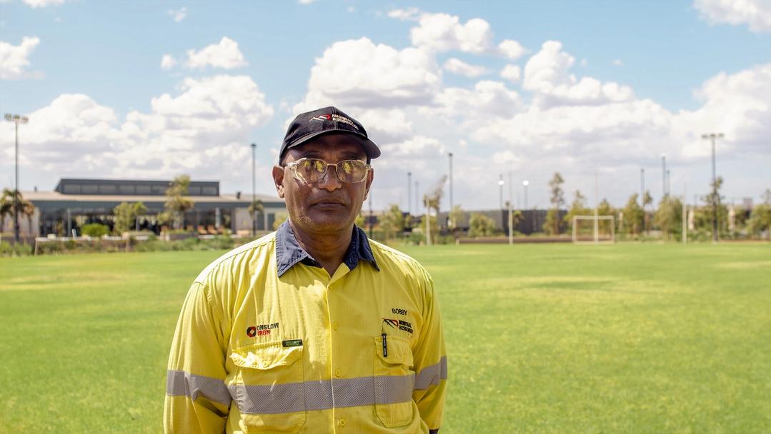 Man in sunglasses and high vis standing on an oval