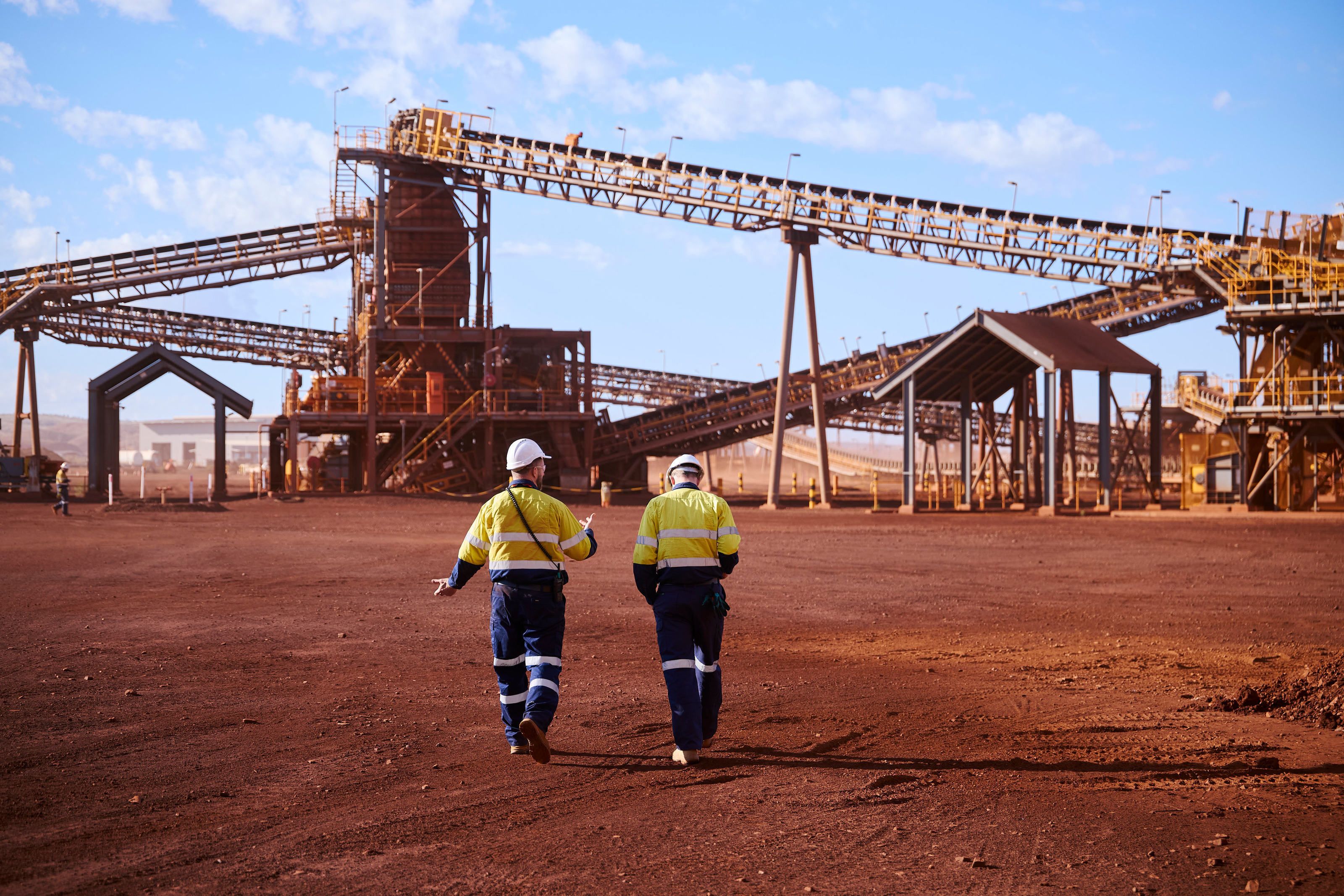 two people in high vis walking towards a mining crusher