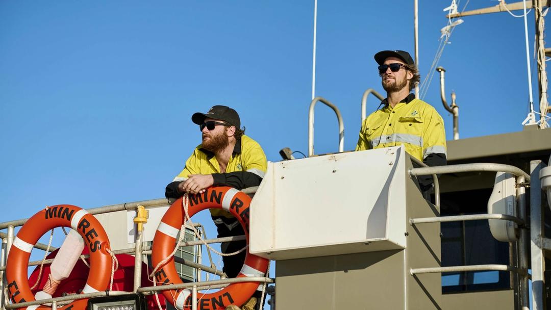 two men standing on a boat looking out