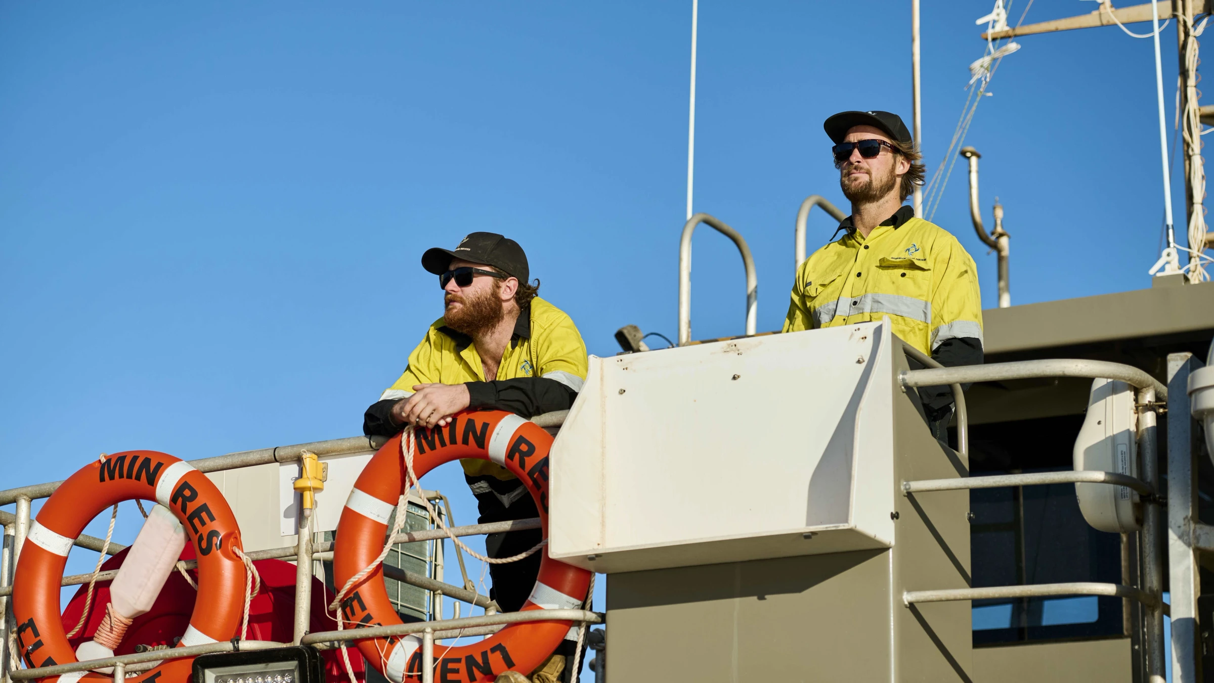 two men standing on a boat looking out