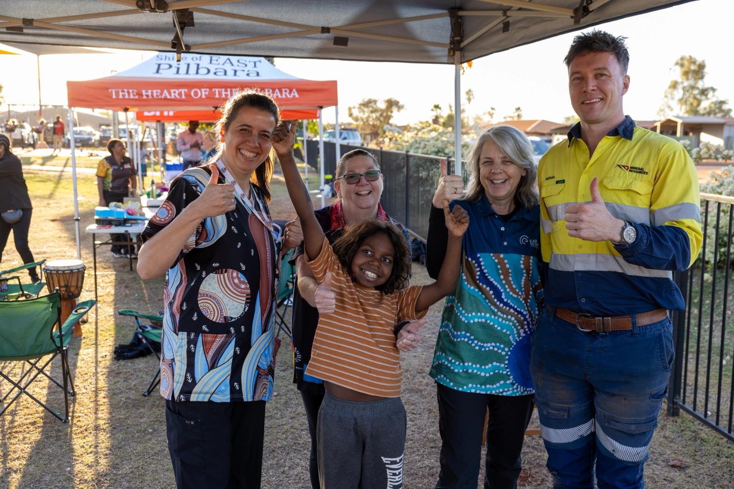 Five people standing together with their thumbs up
