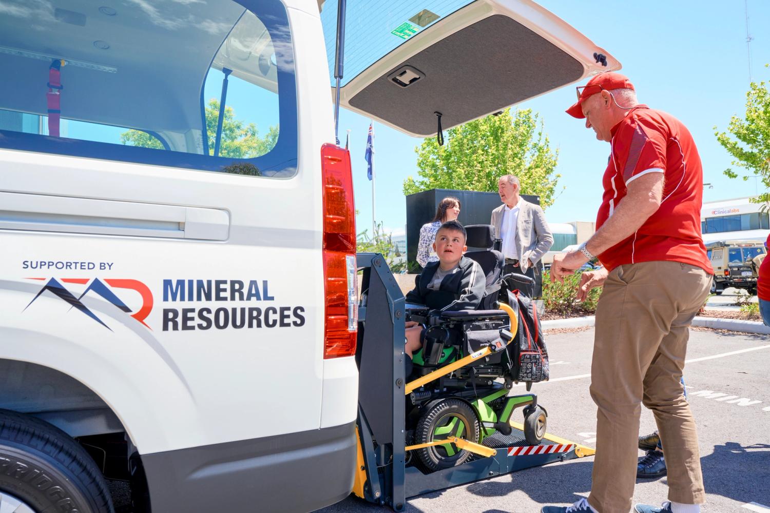 A boy being loaded into a van in his wheelchair