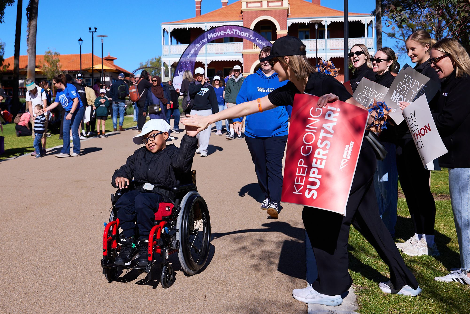 Child in a wheelchair high fiving a woman