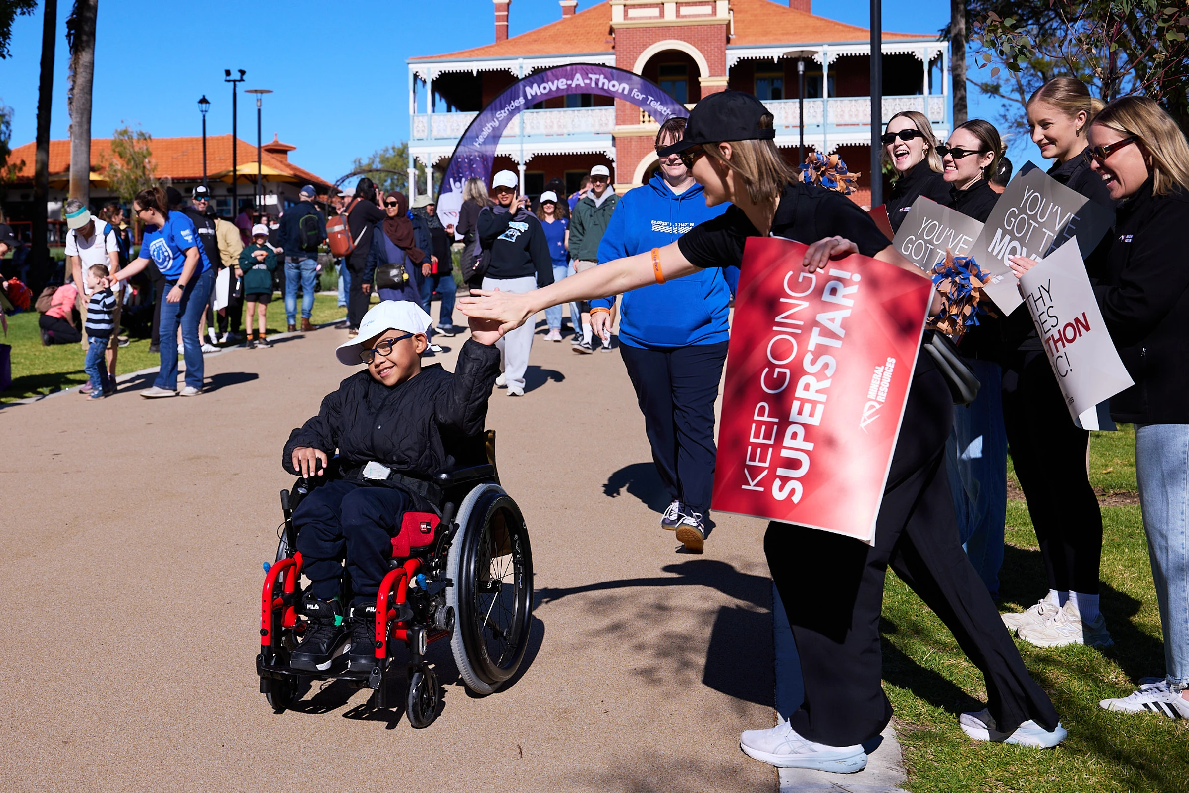 Child in a wheelchair high fiving a woman