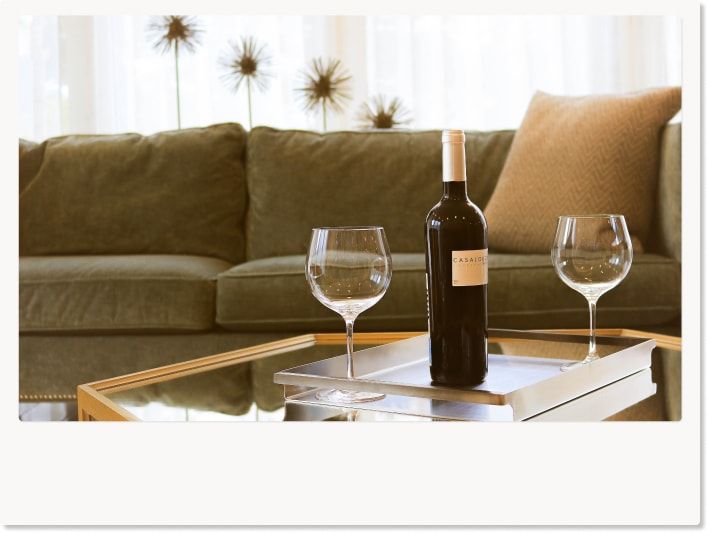 ホテルのソファーの前にワイングラスとワインボトルが置いてある様子