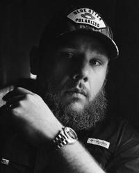 A black and white photograph of Luke Combs in blue otter polarized camo cap and black columbia shirt.