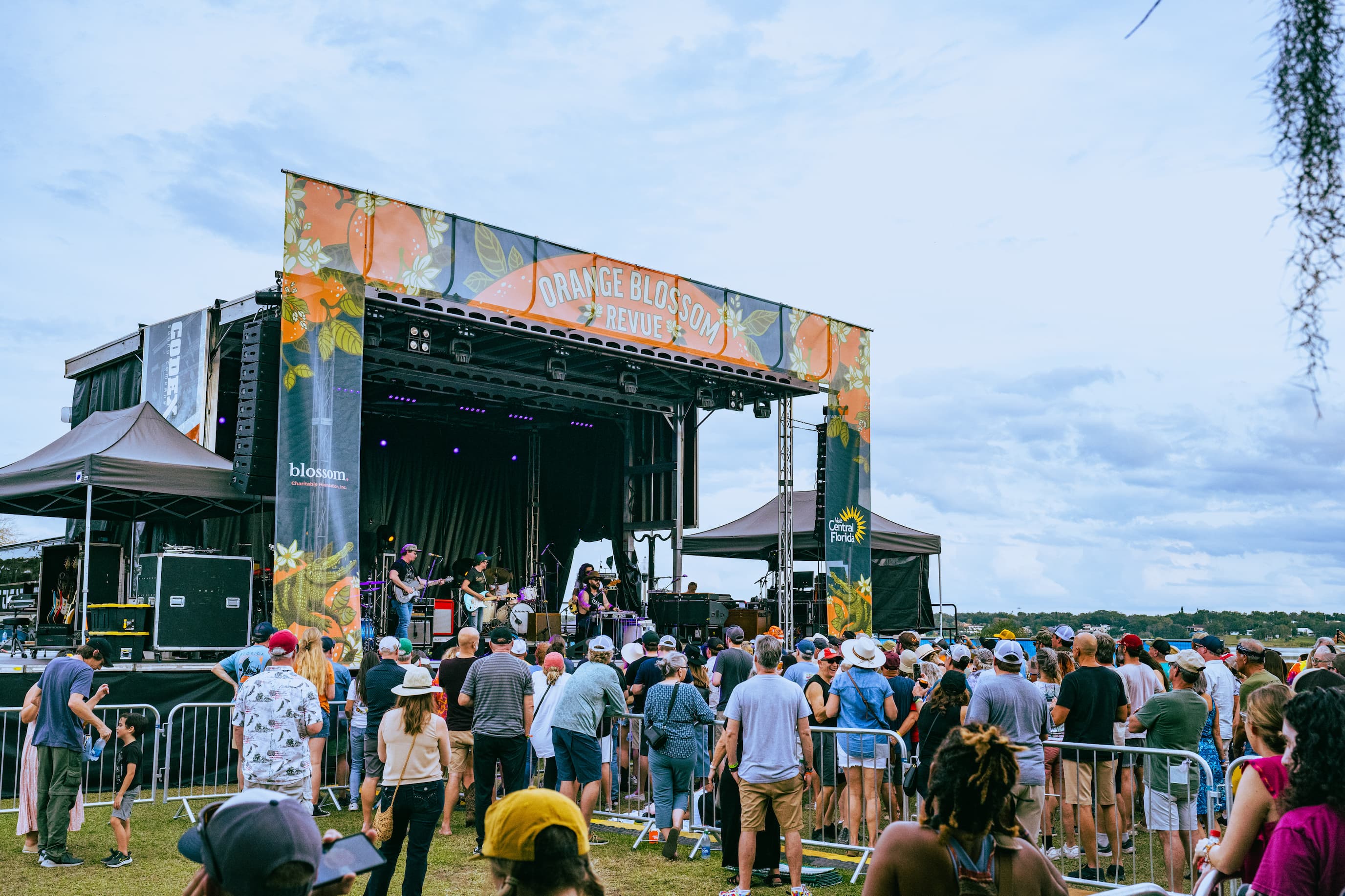 A field of people all staring in one direction with their hands and drinks in the air.