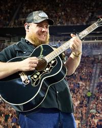 Luke Combs grimacing while playing guitar 