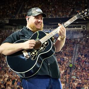 Luke Combs grimacing while playing guitar 