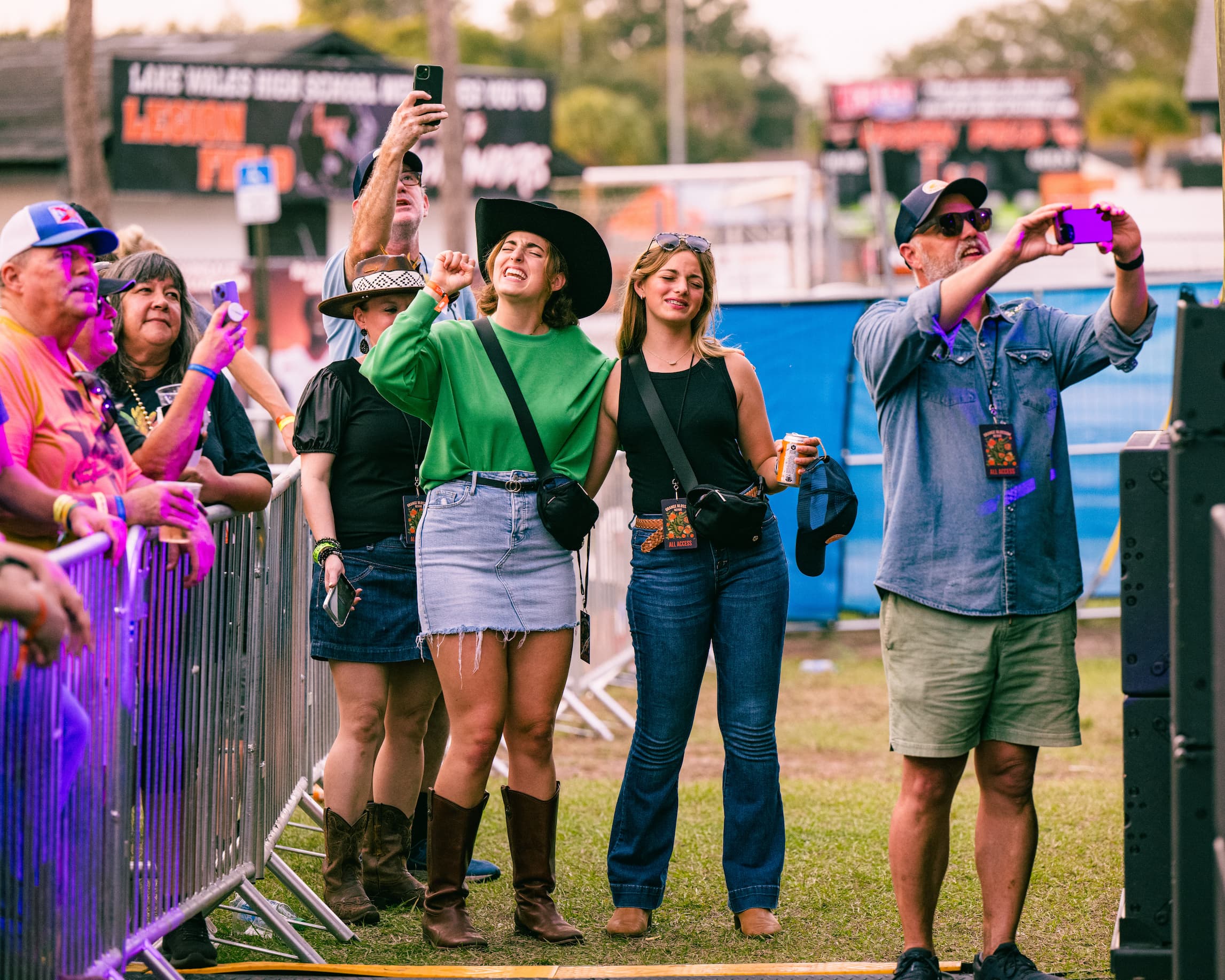 A field of people all staring in one direction with their hands and drinks in the air.