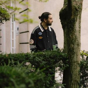 Noah Kahan behind a hedge