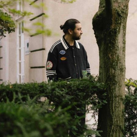 Noah Kahan behind a hedge