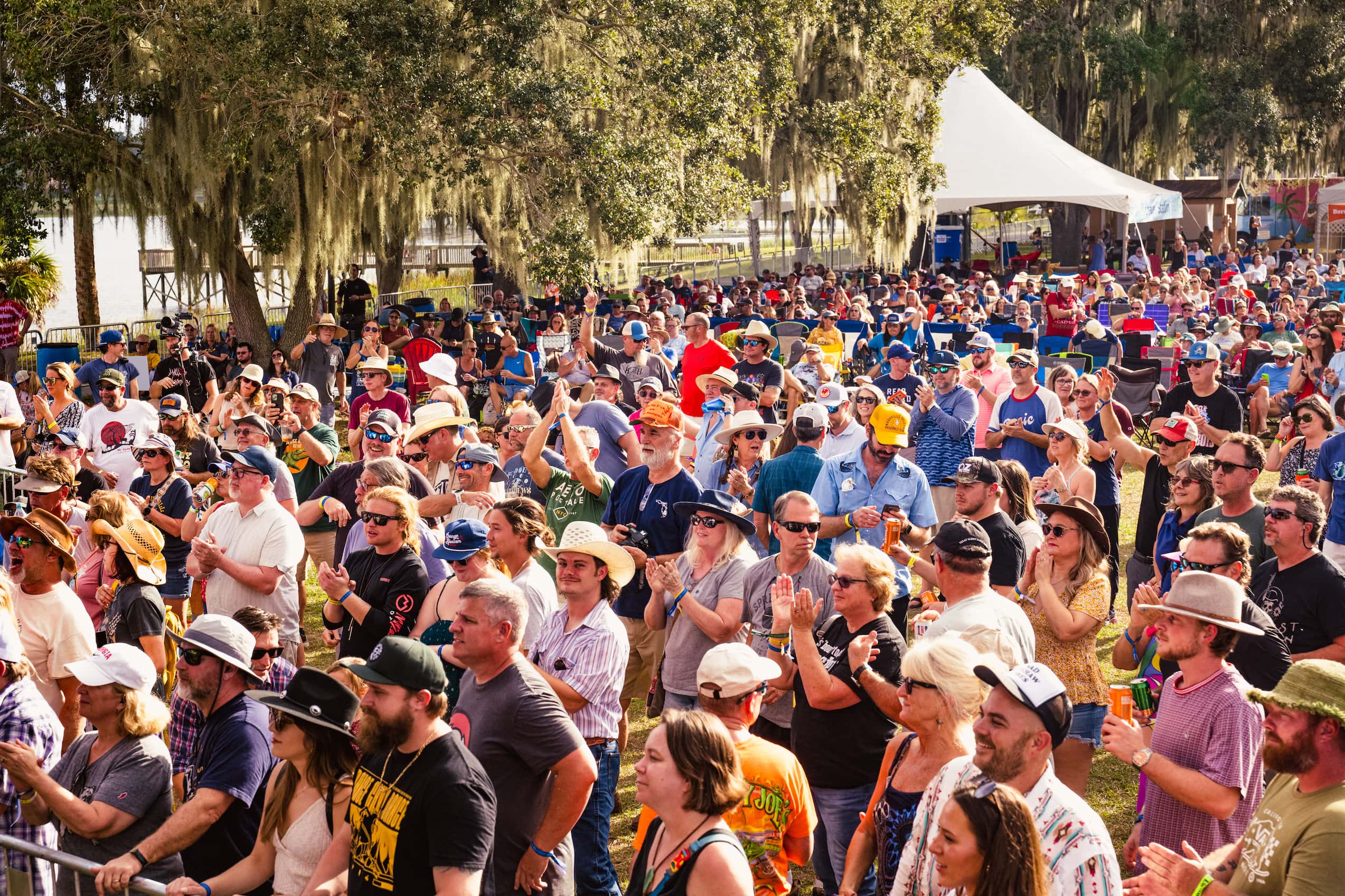 A field of people all staring in one direction with their hands and drinks in the air.