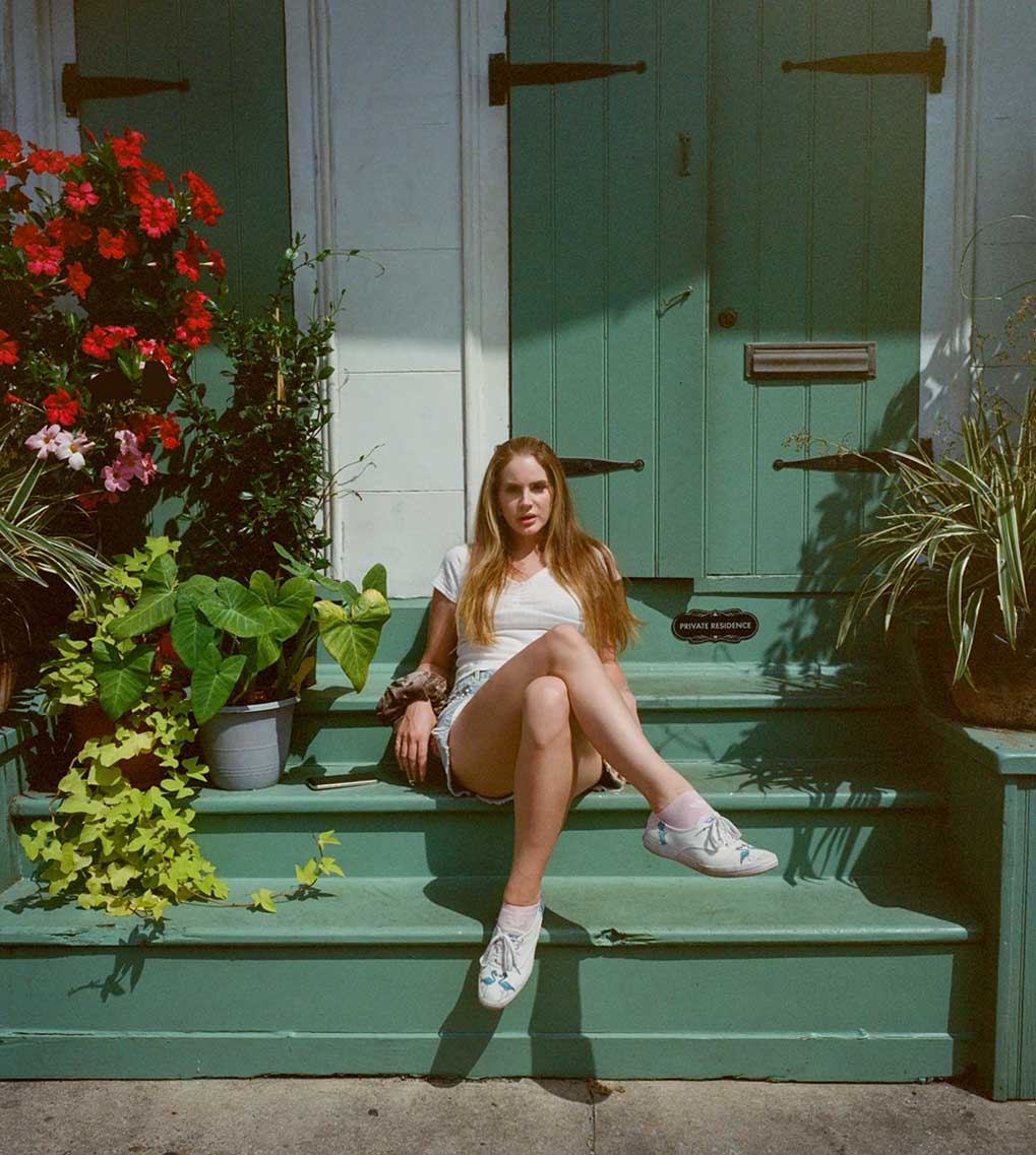 Lana Del Rey sat on a green porch