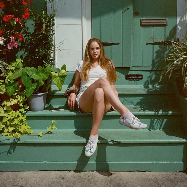 Lana Del Rey sat on a green porch