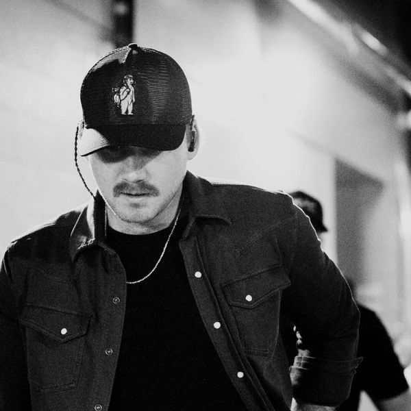 Morgan Wallen looking down wearing a cap in black and white