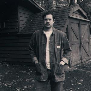 Blurry black and white photo of Michael Marcagi stood outside a barn