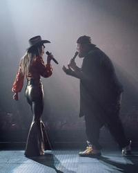 Lainey Wilson and Jelly Roll silhouetted on stage during a live performance