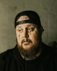 Jelly Roll wearing a backwards ball cap looking off camera