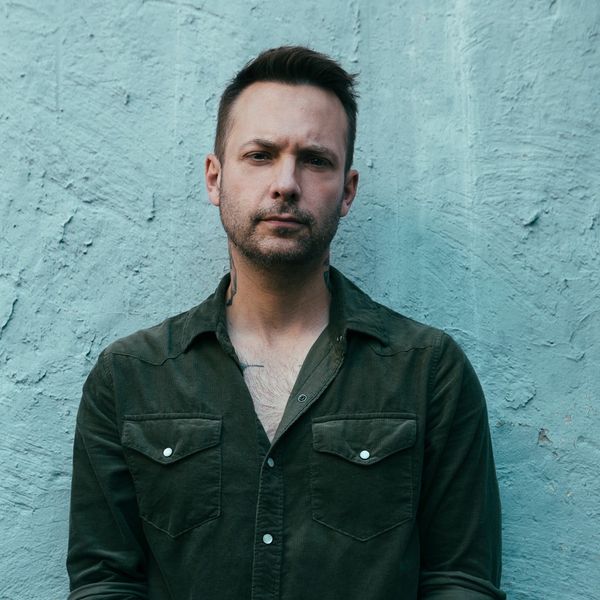 Dallas Smith standing in front of a blue wall. 