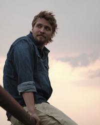 Luke Grimes sat on a fence in Montana
