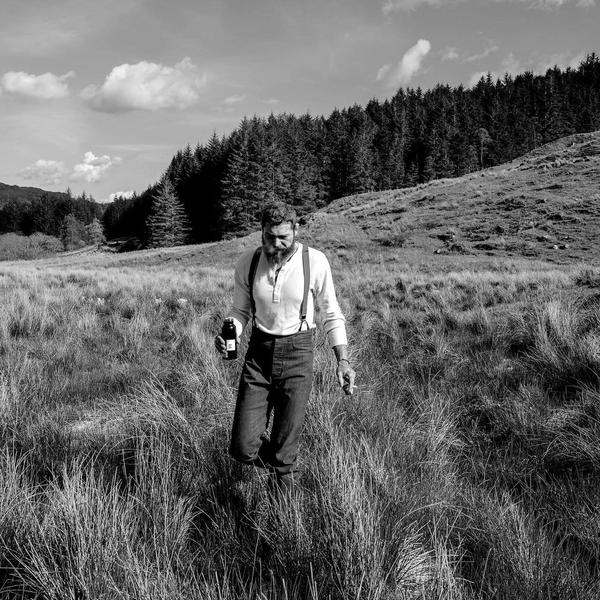 Post Malone in a field in black and white.
