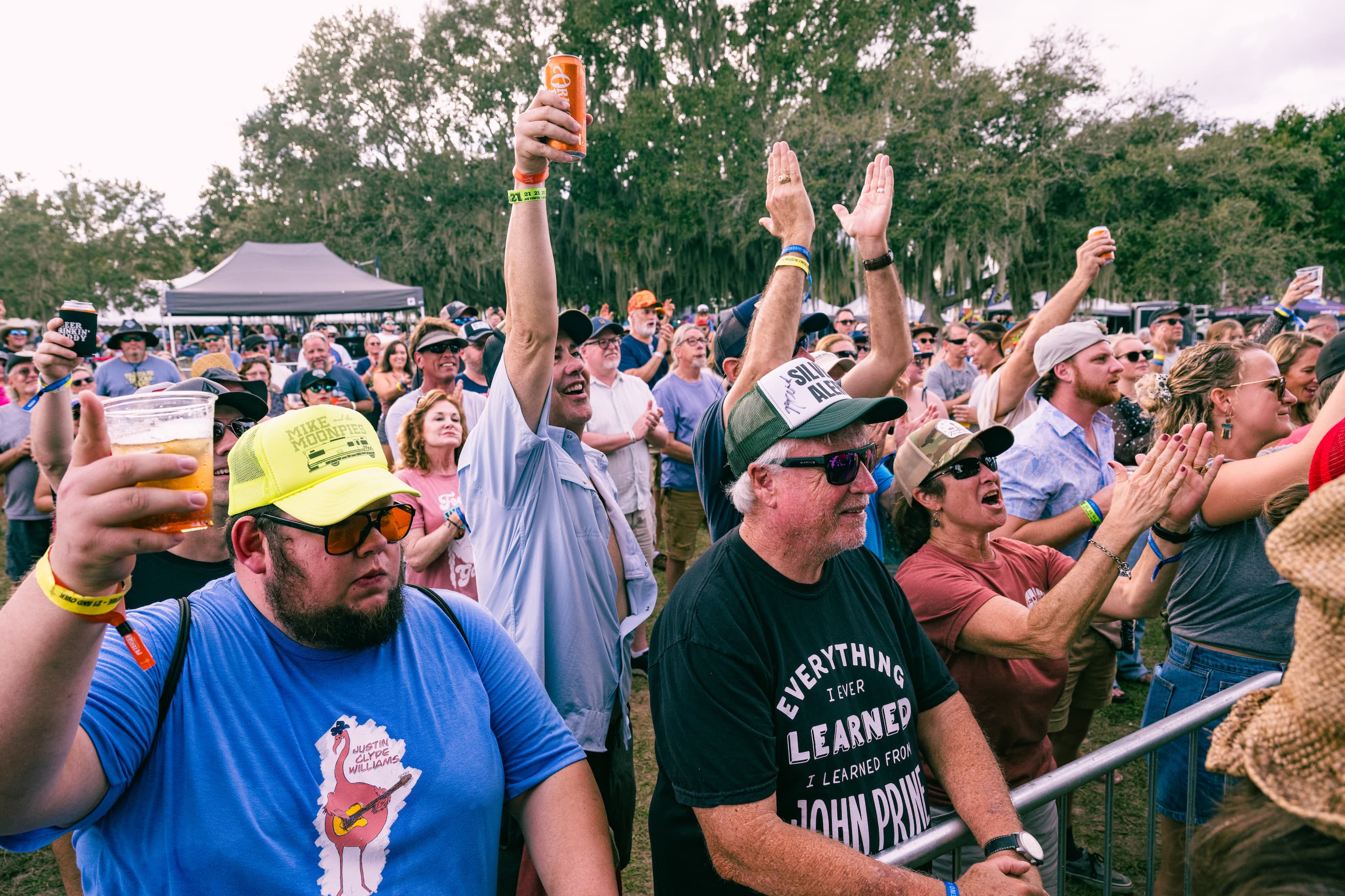 A field of people all staring in one direction with their hands and drinks in the air.